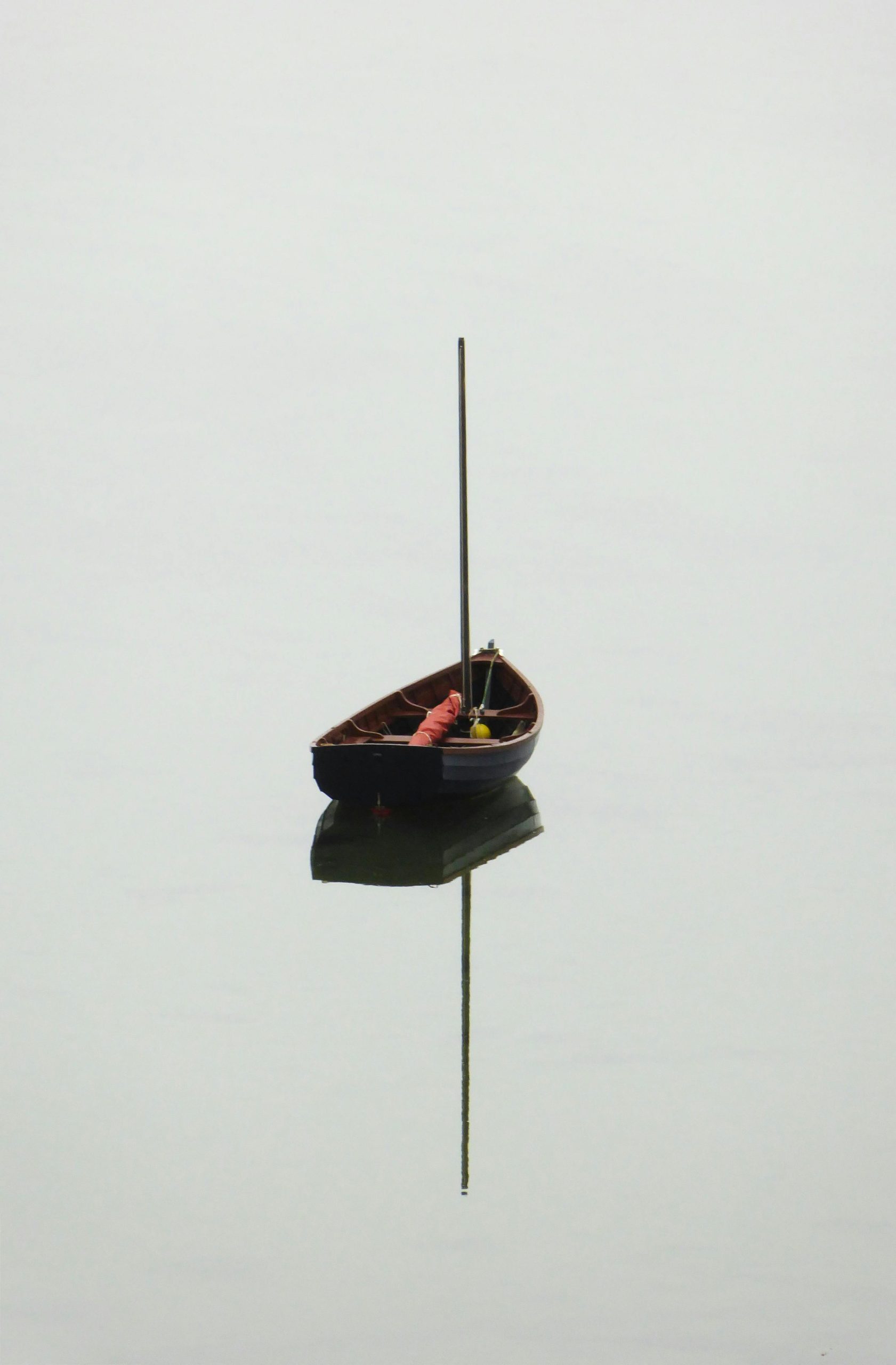 Solitary boat floats on calm water with a perfect reflection, creating a serene and tranquil scene.